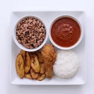 Rice, beans, stew, fried chicken drumstick and plantain
