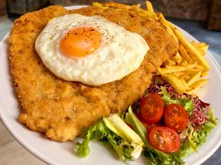 Schabowy XXL pod sadzonym jajkiem z frytkami i surówką