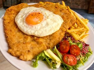 Schabowy XXL pod sadzonym jajkiem z frytkami i surówką