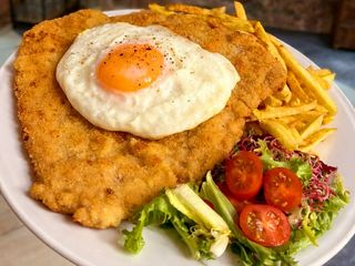 Schabowy XXL pod sadzonym jajkiem z frytkami i surówką