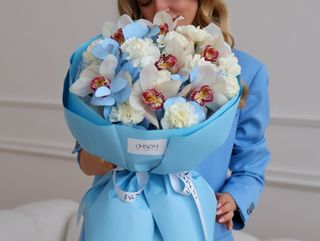 Bukiet z białych goździków, storczyków cymbidium oraz niebieskiego eukaliptusa.