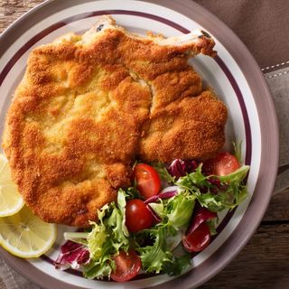 Schabowy z kością podawany z ziemniakami gotowanymi i surówką