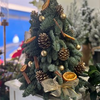 Pinheiro pequeno decorado com pinhas, canela e laranjas 