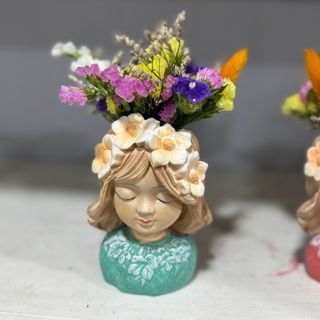 Boneca pequena de cerâmica com flores secas 