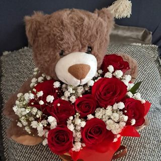Cesto com urso castanho e rosas.