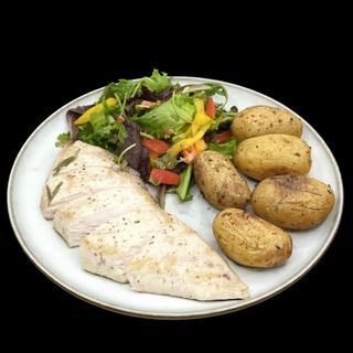 Peito de frango com salada verde e batatas pequenas assadas.