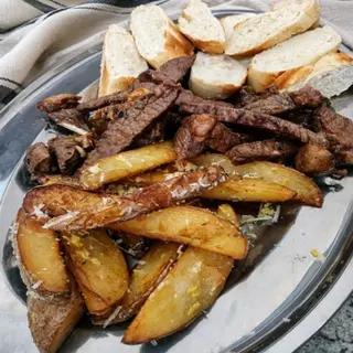 Porção de picanha com batata rústica e baguete assada na hora