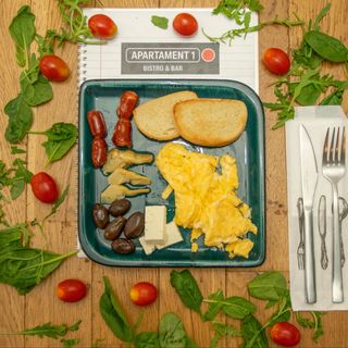 Scrambled eggs cu cârnăciori, feta, hummus şi măsline