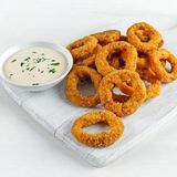 Inele de ceapă crocante servite cu sos de mărar. Aurii, ușor dulci, imposibil de împărțit.