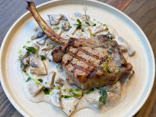 Tomahawk de porc cu ciuperci și cartofi prăjiți cu parmezan