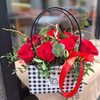 Torbica sa crvenim ružama i dekorativnim zelenilom