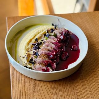 Качина грудка з вершковою полентою та вишневим соусом