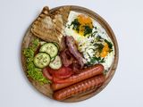 Яєчня з беконом,сосисками , овочами  та грінками .