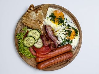 Яєчня з беконом,сосисками , овочами  та грінками .