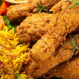 Two piecer drumsticks chips and rice with a soda