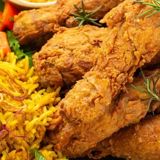 Two piecer drumsticks chips and rice with a soda