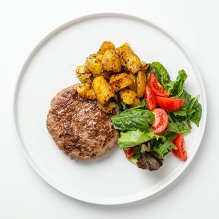 Hamburger al piatto, patate al forno e insalata