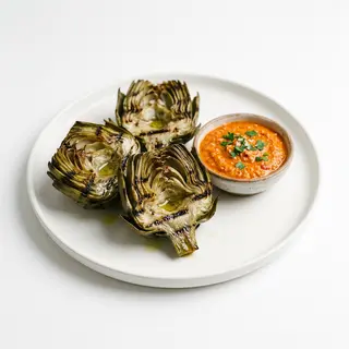 Corazones de alcachofas confitados a la brasa con romesco