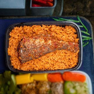 Jollof rice with fried plantain, salad and cow head or tail