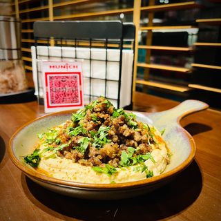 Ground beef with hummus, crusty baguette and colorful cabbage garnish
