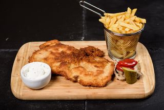 Şniţel de porc gigant servit cu cartofi prăjiți și smântână