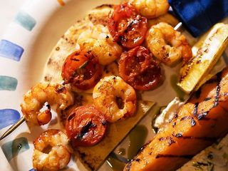 Сувлакі з лангустинів з грильованими томатами чері із запеченим бататом, пряним грецьким йогуртом та пітою (180г)