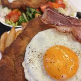 Schabowy z jajkiem sadzonym i bekonem z frytkami i sałatką