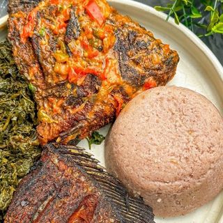 Brown ugali served with fish in Nigerian stew and managu mixed with terere 