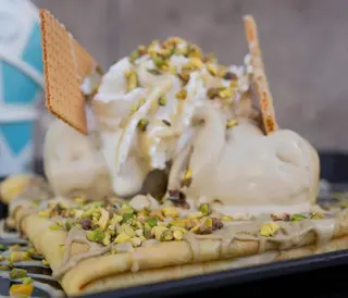 Crêpes con gelato, nocciola, gelato, pistacchio e granella e panna
