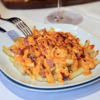 Patatas fritas con queso cheddar y trozos de bacon