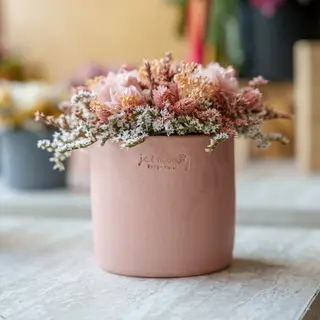 Vaso pequeno rosa com as flores preservadas rosa