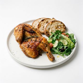 Mezzo pollo con pane e insalate