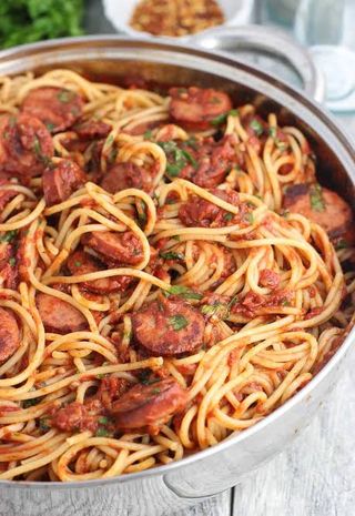 Spicy spaghetti with sliced chicken sausages served with a soda 