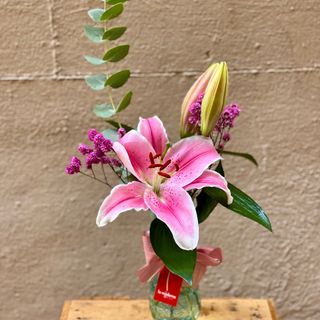 Jarrón de cristal con lilium rosa y verdes.