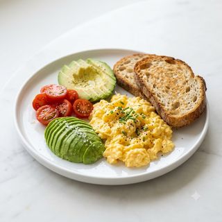 Plato De Huevos Revueltos Con Aguacate, Tomate Y Rebanadas De Pan