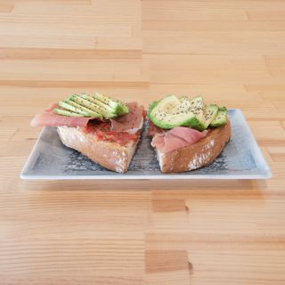 Desayuno de tostada de tomate, jamón y aguacate