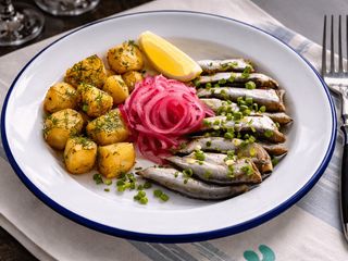 Тюлька з печеною картоплею, зеленою цибулькою і пряним маслом (250g)
