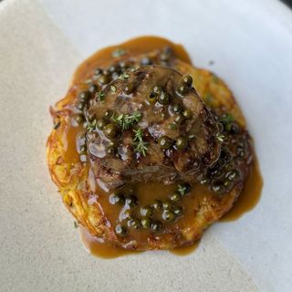 Solomillo a a parrilla con mil hojas de patata, salsa y salsa de pimienta verde.