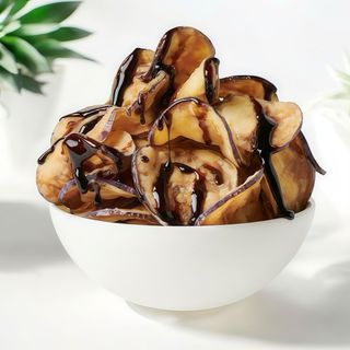 Chips de berenjenas con base de romescu bañadas en chili mango.