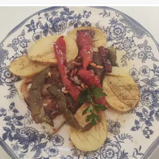 Bacalao al horno con cebolla caramelizada, piñones y patatas fritas.