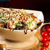 ensalada de pollo empanado, salsa césar, croutons y queso grana padano