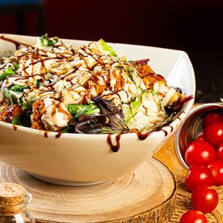 ensalada de pollo empanado, salsa césar, croutons y queso grana padano