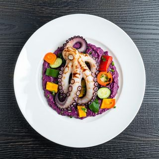 Polpo arrosticciato con base di patata viola e verdure croccanti
