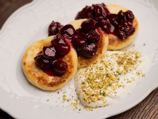 Класичні сирники з вишневим конфі та сметаною