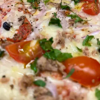 Porción de pizza de atún con guisito de verduras y aceitunas negras.