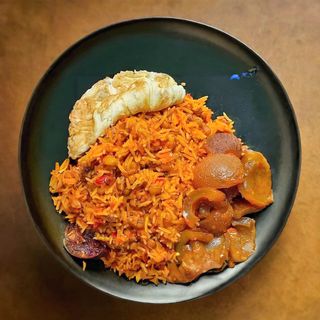 Jollof rice, pan fried egg and peppered pomo