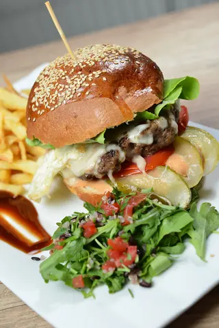 Cheeseburger cu ou servit cu cartofi prăjiți și sos de maioneza hey
