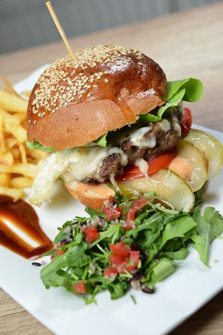 Cheeseburger cu ou servit cu cartofi prăjiți și sos de maioneza hey