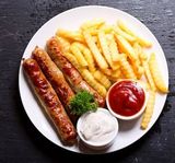 A pair of smoked premium chicken sausages and fries with a soda
