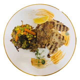 Свинска вратна пържола на тиган върху канапе от рьощи и зеленчуци